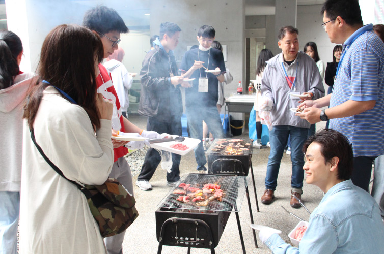 有朋会交流BBQ大会の様子：参加者が皿を片手に歓談している写真