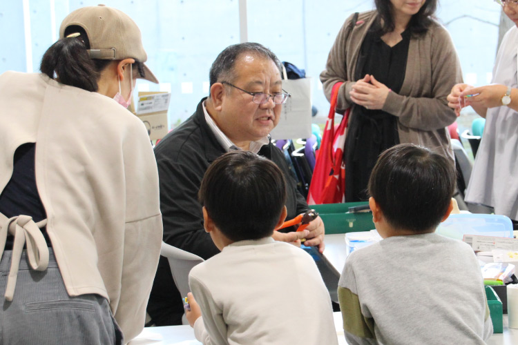 お子様の前でキーホルダーを作成しているスタッフの写真