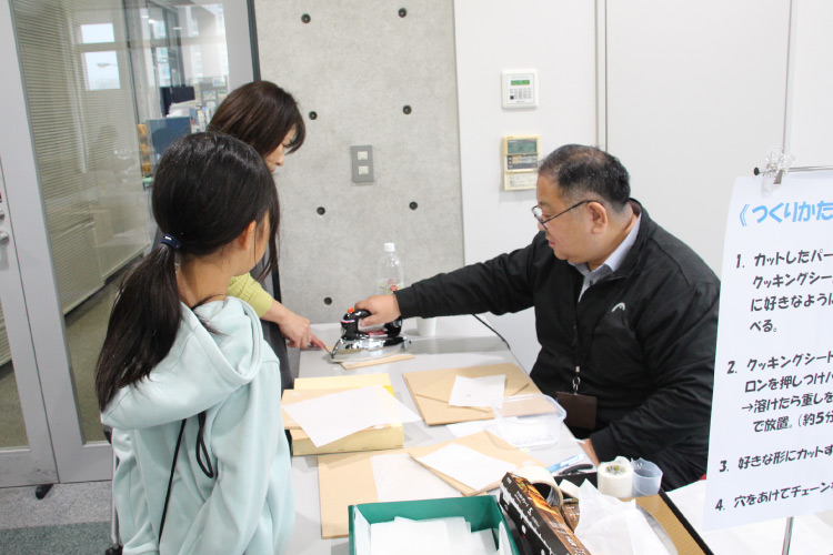 来場者にオリジナルキーホルダーの説明をしているスタッフの写真