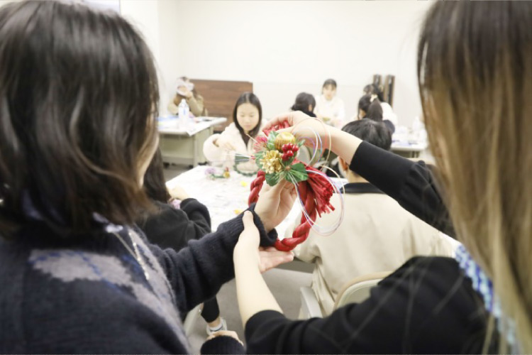 完成したしめ飾りを見せ合う留学生たちの写真